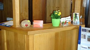 A wooden reception desk with a welcome sign, a small potted plant, and a Crown refrigerator. - CityHotel Magdeburg (Magdeburg)