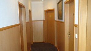 A narrow hallway with wooden doors, carpeted floor, and a ceiling light fixture. - CityHotel Magdeburg (Magdeburg)