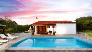Ein modernes Haus mit Swimmingpool, einer Terrasse mit Liegestühlen und einem Garten.