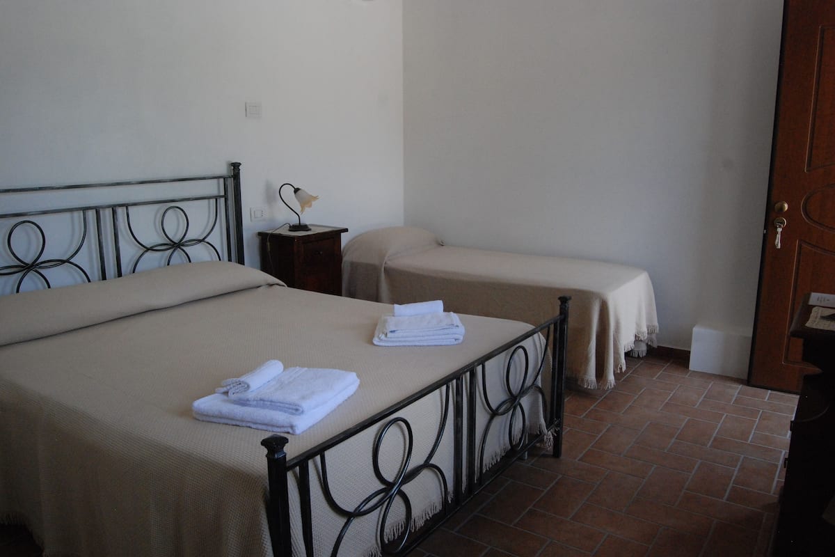 Una habitación con una cama, una mesita de noche con una lámpara y una puerta.