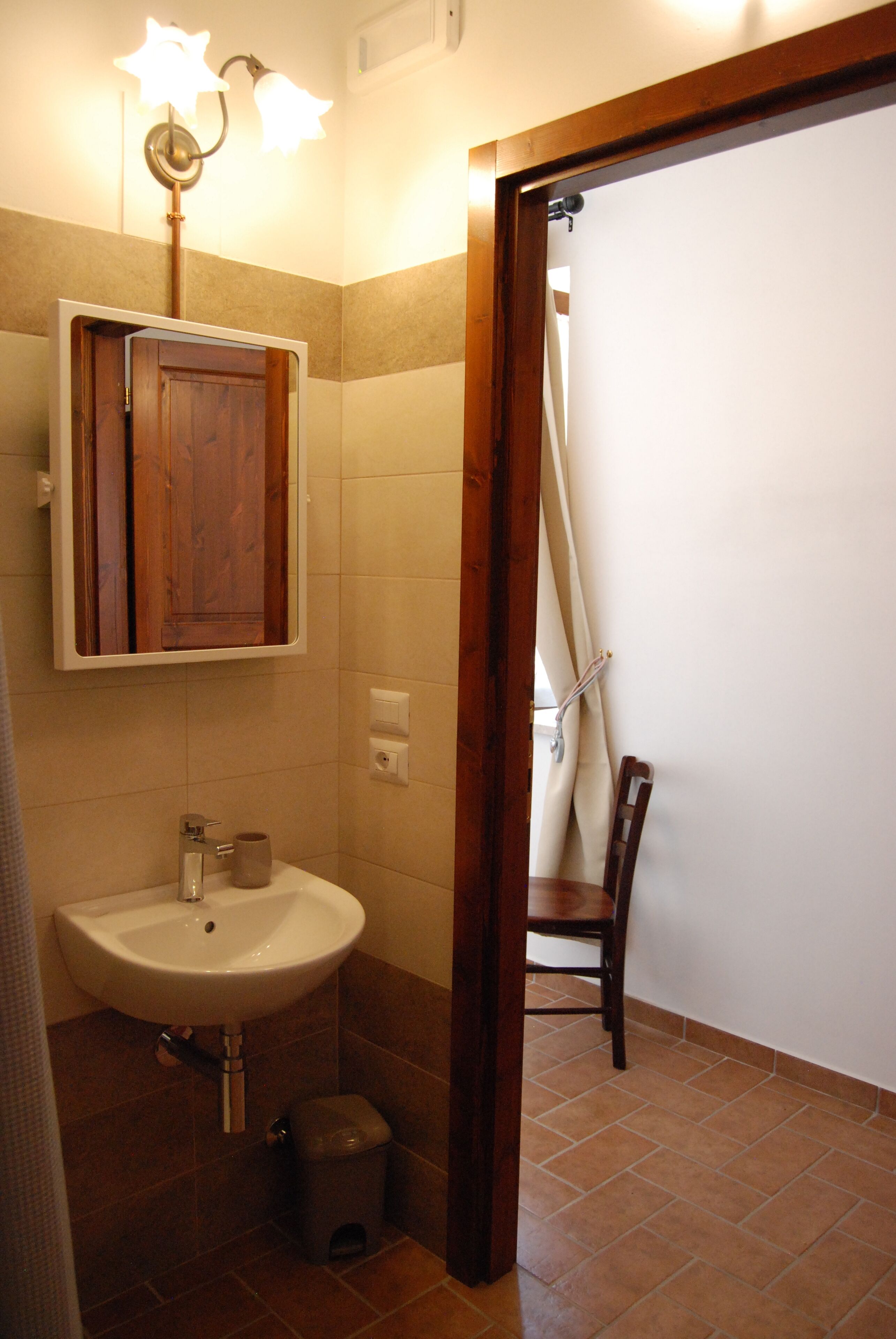 A bathroom with a wooden cabinet, a sink, and a chair.