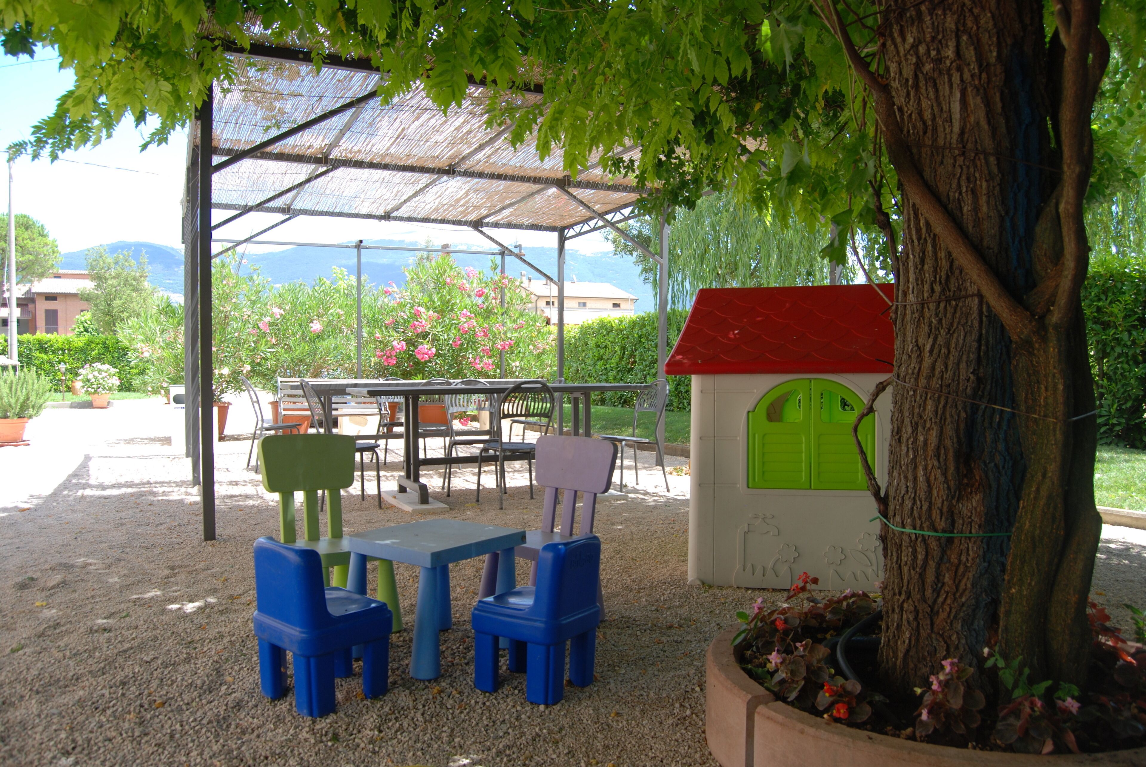 An outdoor seating area with a table and chairs, a small tree, and a decorative house-like structure.