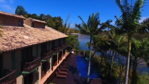 A hotel with a tiled roof, a pool, and palm trees. - Engenho da Lagoa Pousada (Garopaba)