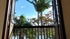 A balcony with a view of palm trees and a clear sky. - Engenho da Lagoa Pousada (Garopaba)