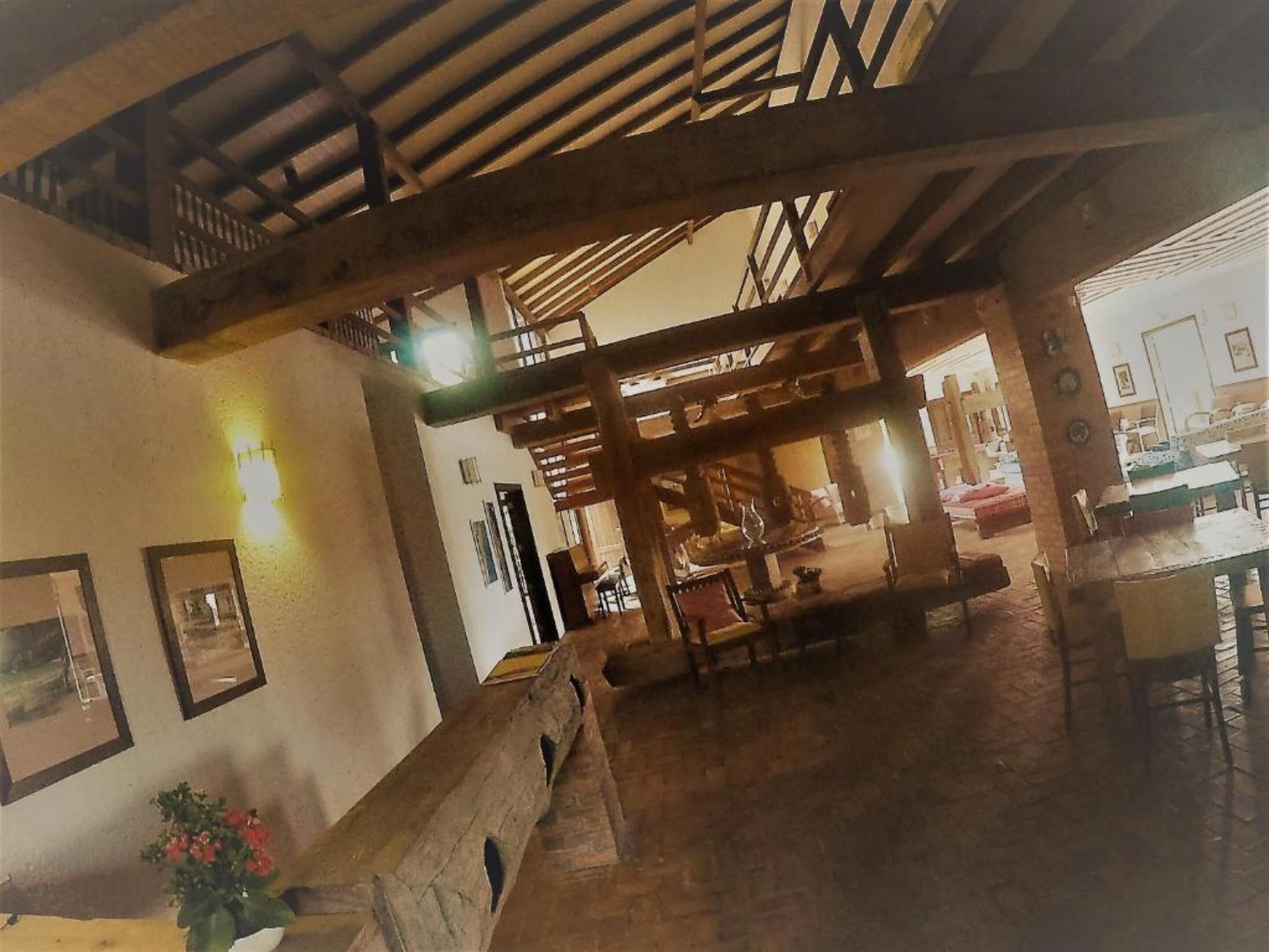 A spacious interior with a high ceiling, wooden beams, and a dining area with tables and chairs.