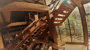 A spiral staircase with wooden railings in a room with a tiled floor and large windows. - Engenho da Lagoa Pousada (Garopaba)