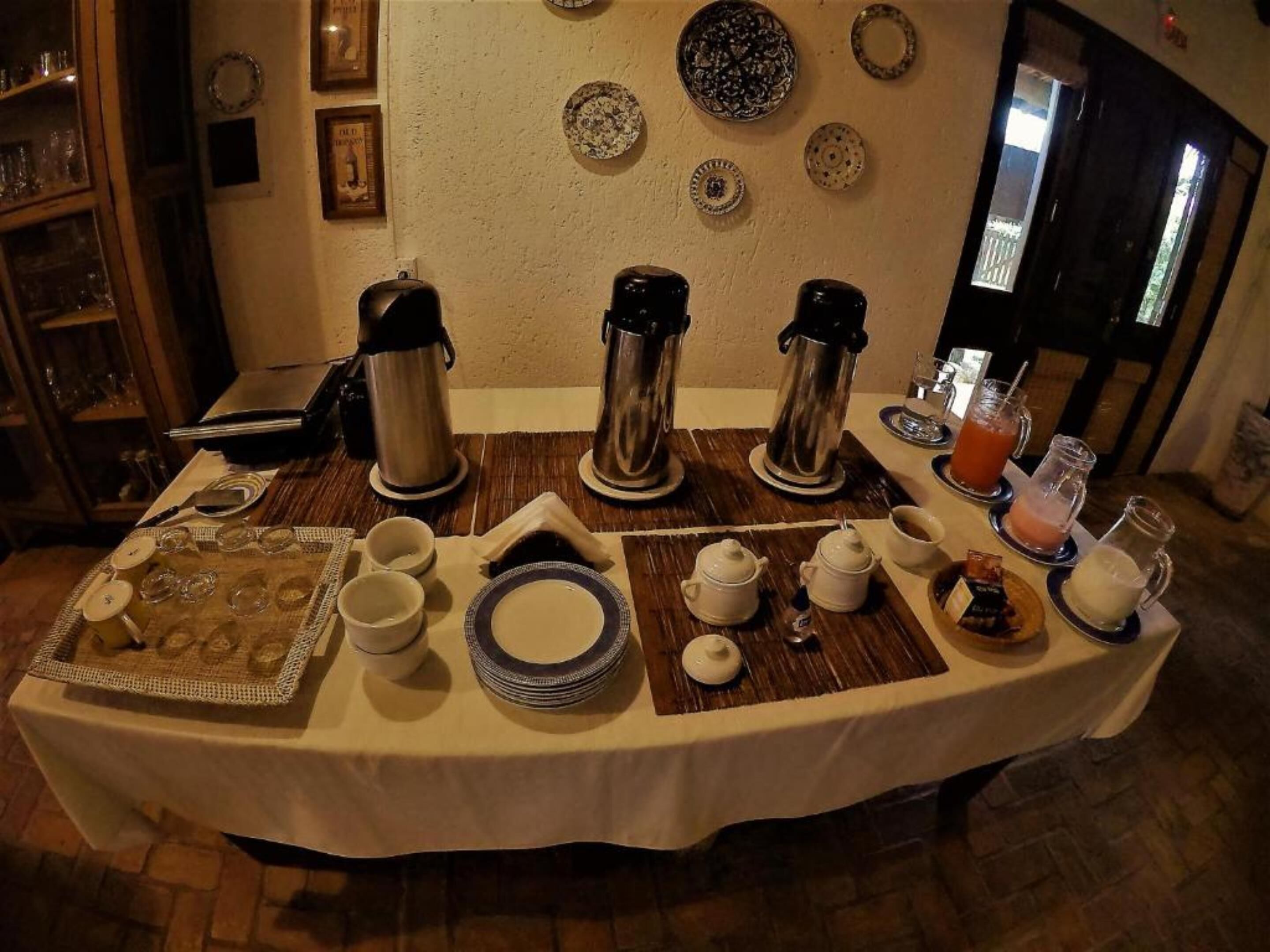 Mesa de comedor dispuesta con distintos platos, tazas y una estación de café.