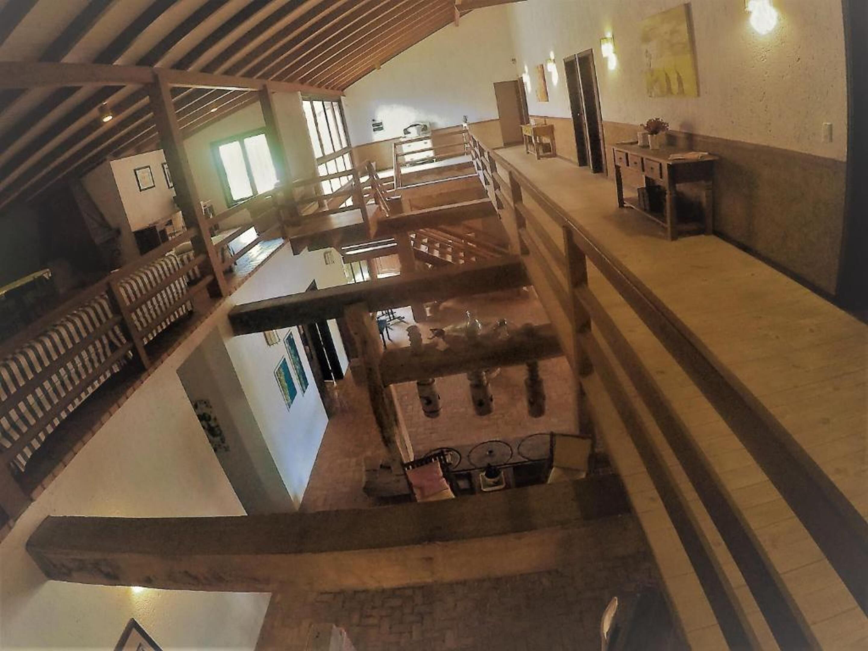 Un amplio atrio con techo alto, vigas de madera y una escalera central.