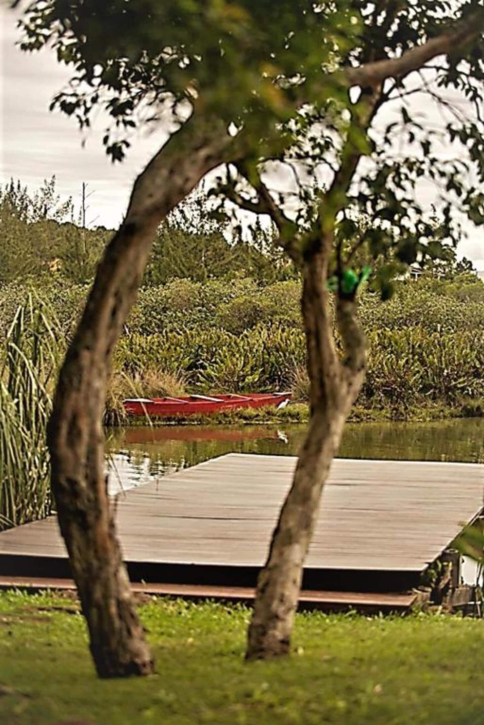 A dock extending into a calm body of water with a red boat moored at the end.