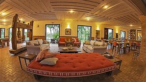 A spacious living area with a large red sofa, multiple seating options, and a wooden ceiling. - Engenho da Lagoa Pousada (Garopaba)