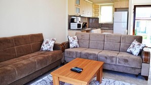 A living room with two sofas, a coffee table, and a kitchen in the background.