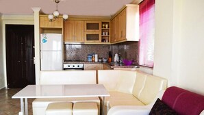 A compact kitchen with a dining area, a refrigerator, a stove, and wooden cabinets.