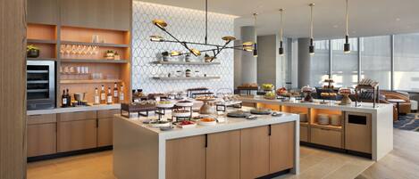 Una cocina moderna con una isla central, armarios de madera y diversos alimentos exhibidos en estantes y encimeras.