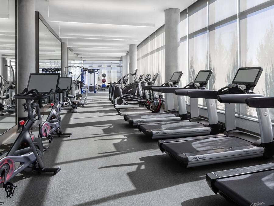 Une salle de sport équipée de tapis de course, de vélos d’appartement et d’appareils de musculation elliptique.