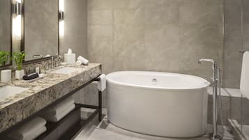A modern bathroom with a freestanding bathtub, a marble sink, and a large mirror.