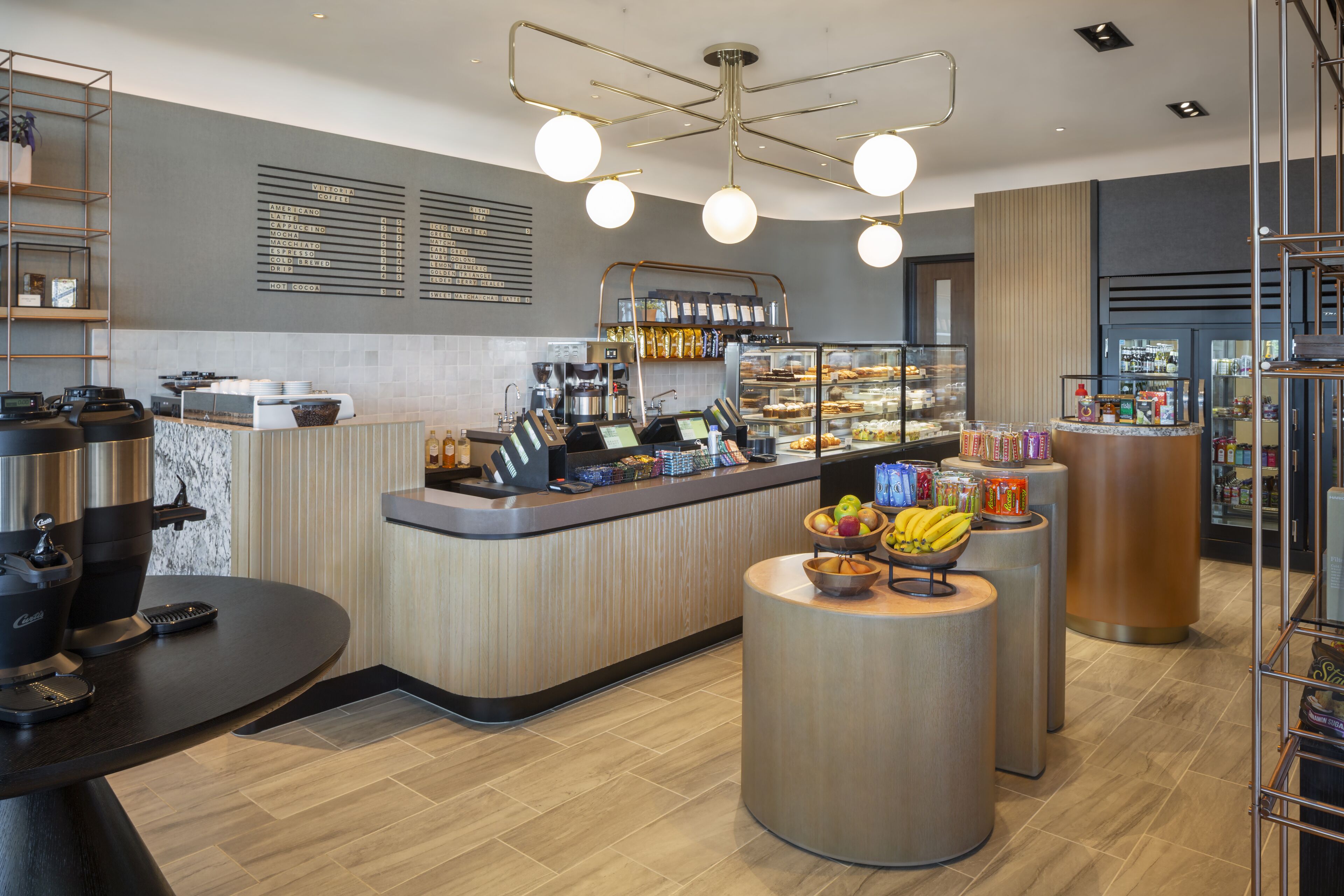 Un café moderne avec un comptoir, des machines à café et un présentoir de fruits.