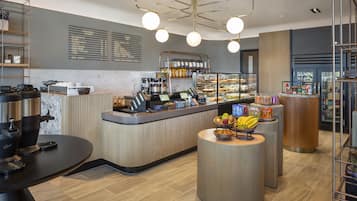 Un café moderne avec un comptoir, des machines à café et un présentoir de fruits.