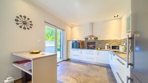 A modern kitchen with white cabinets, a built-in oven, and a microwave. - Villa Adrimar (Vrbnik)