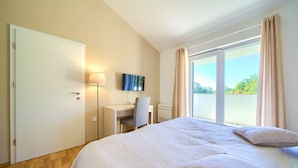 A hotel room with a bed, desk, chair, TV, and a large window with curtains. - Villa Adrimar (Vrbnik)