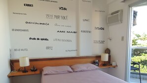 A hotel room with a bed, pillows, a nightstand, a lamp, and motivational wall art. - Praia das Dunas Apartamento Aconchegante 2 Quartos (Cabo Frio)