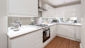 Una cocina moderna con armarios blancos, una estufa de acero inoxidable y piso de madera.