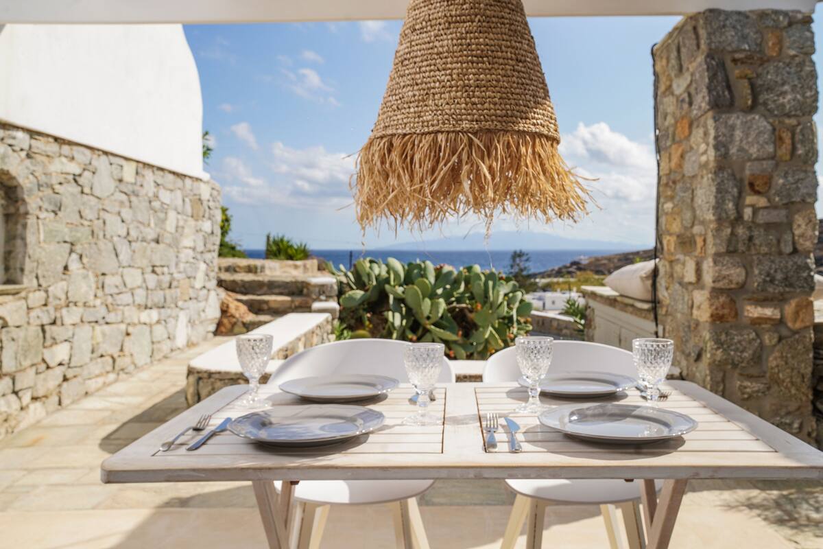 An outdoor dining area with a table set for two, overlooking a scenic view.