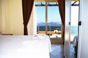 A hotel room with a bed, a sliding glass door leading to a balcony with a view of the sea and mountains. - 1 Bedroom Apartment Sea View 9 by Likya Global (Milas)