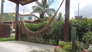 A hammock under a wooden structure, surrounded by lush greenery and a cactus. - Casa Cabo Frio Aconchegante 5min Praias (Cabo Frio)