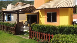 A row of yellow houses with tiled roofs, a wooden fence, and a clear sky. - Casa Cabo Frio Aconchegante 5min Praias (Cabo Frio)