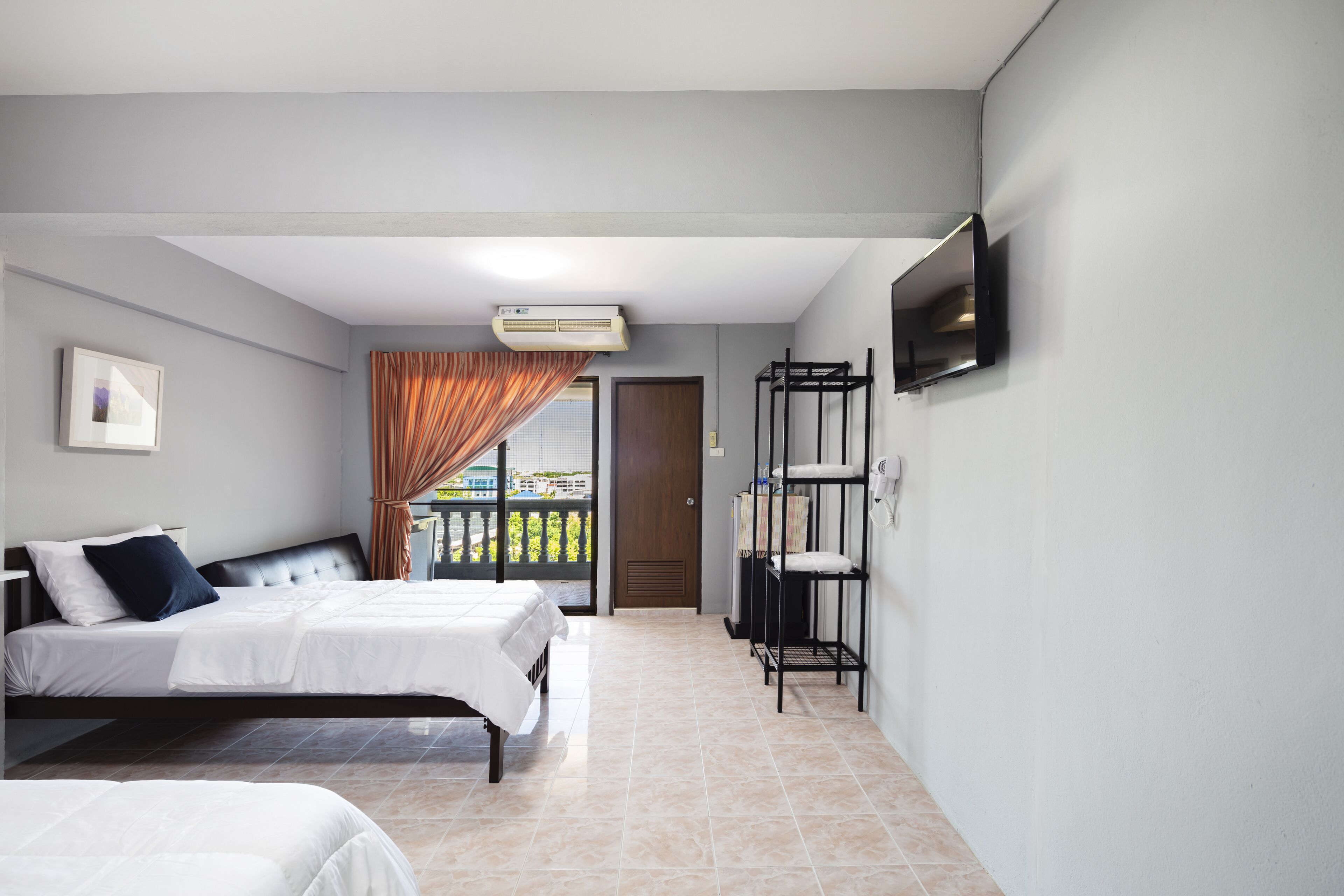 Hotelkamer met een bed, een aan de muur bevestigde televisie, een plafondventilator en uitzicht.