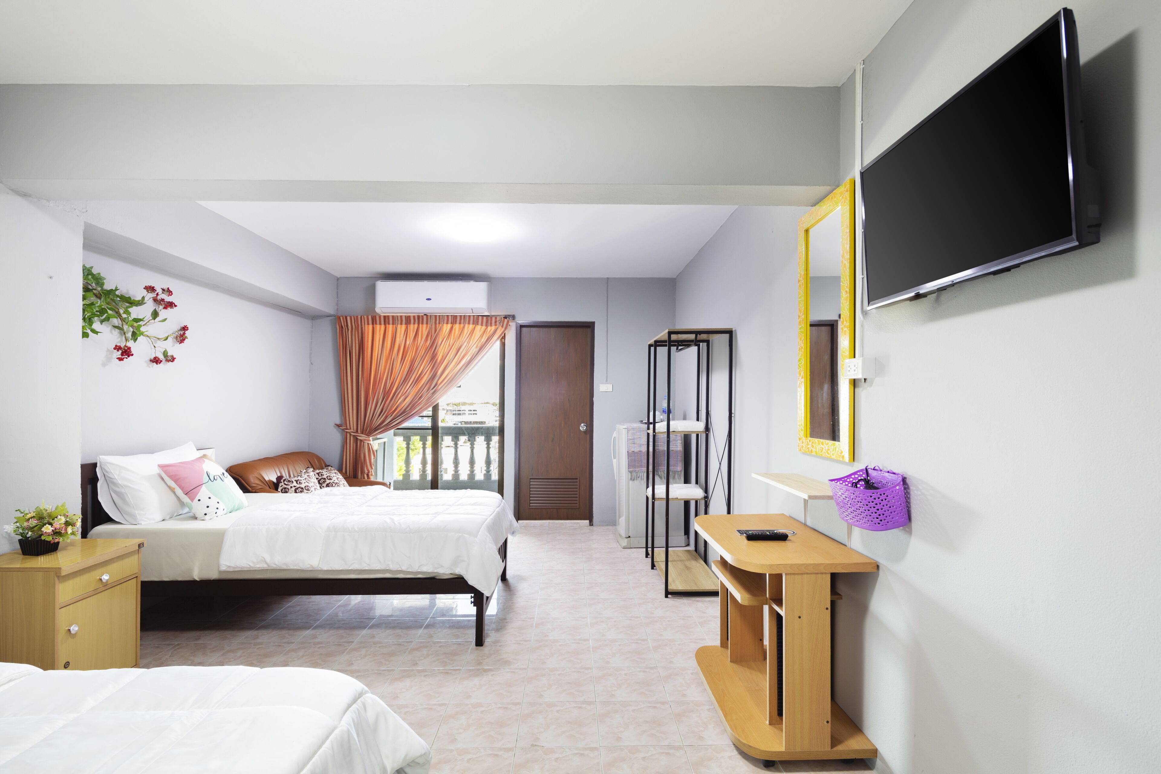 Ein Hotelzimmer mit zwei Betten, einem Fernseher, einem Schreibtisch und einem Spiegel.