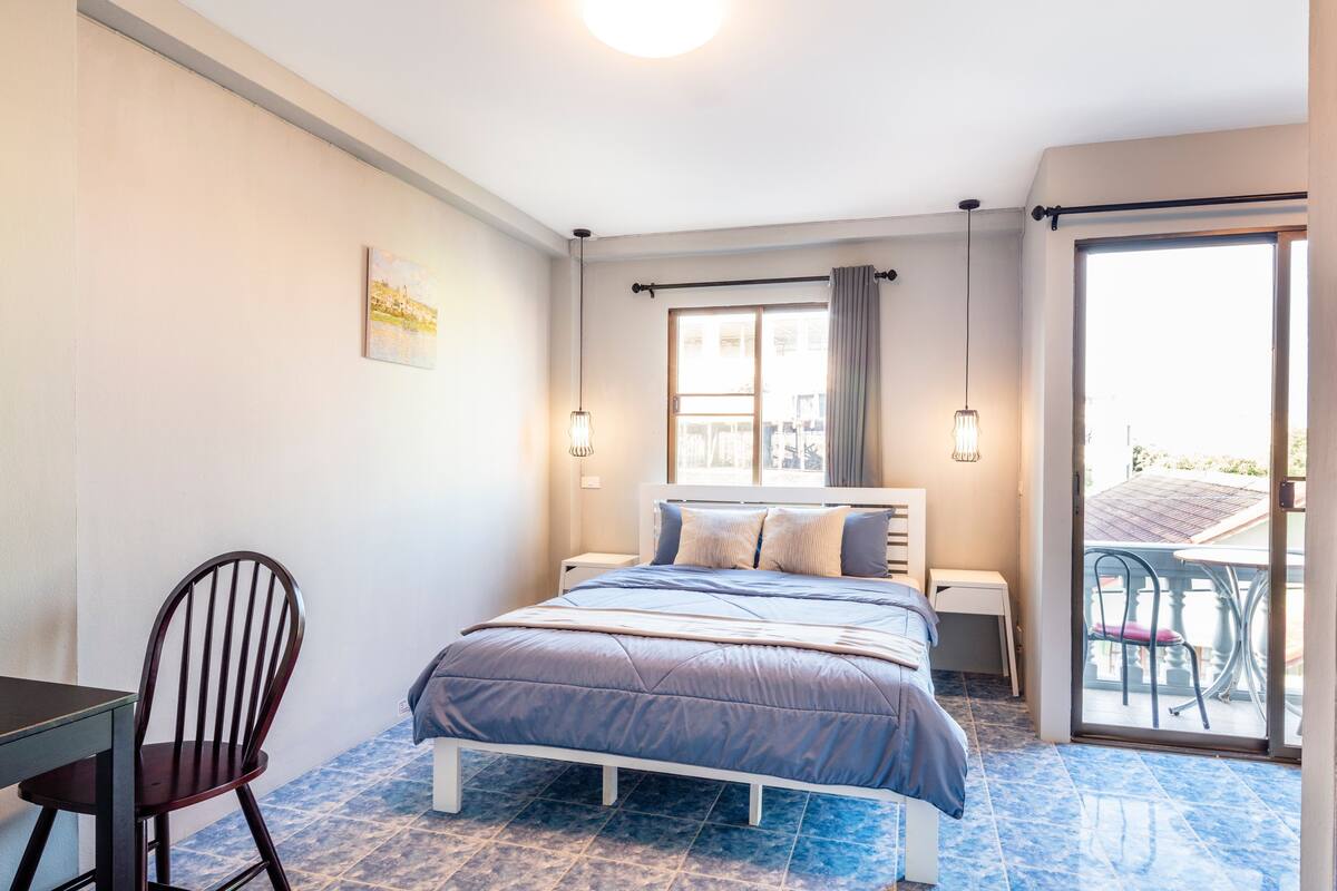 A bedroom with a bed, a chair, a desk, and a window.
