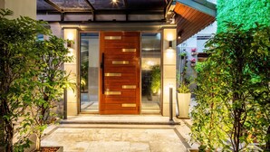 Une entrée moderne avec une porte en bois, des panneaux de verre et un chemin pavé.