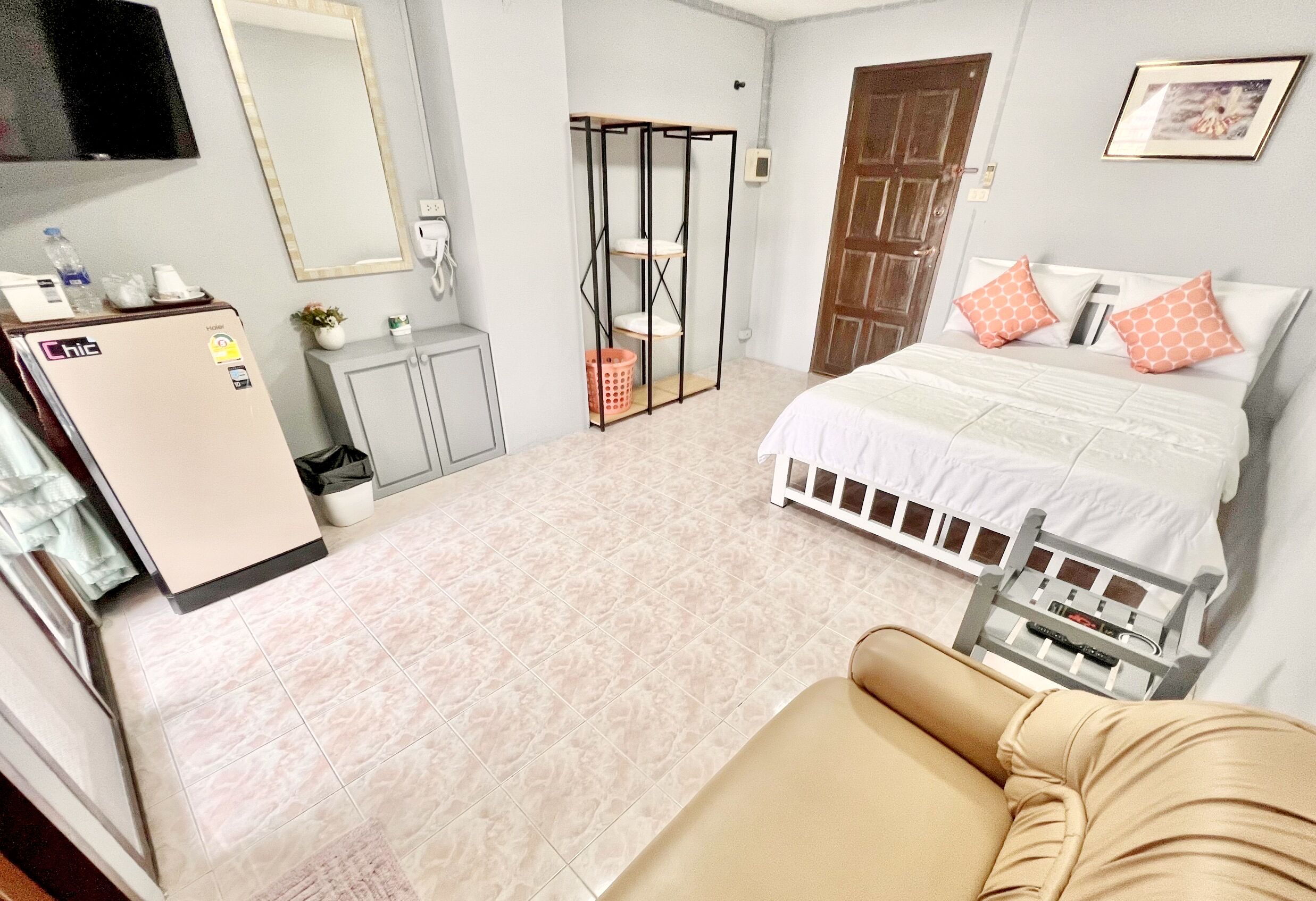 A hotel room with a bed, a sofa, a TV, a wardrobe, and a small table with a remote control.