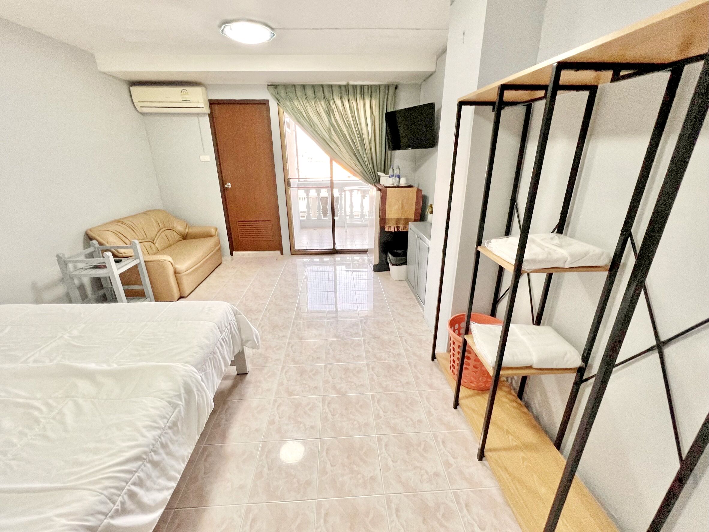 A hotel room with a bed, a sofa, a TV, and a balcony with a view.