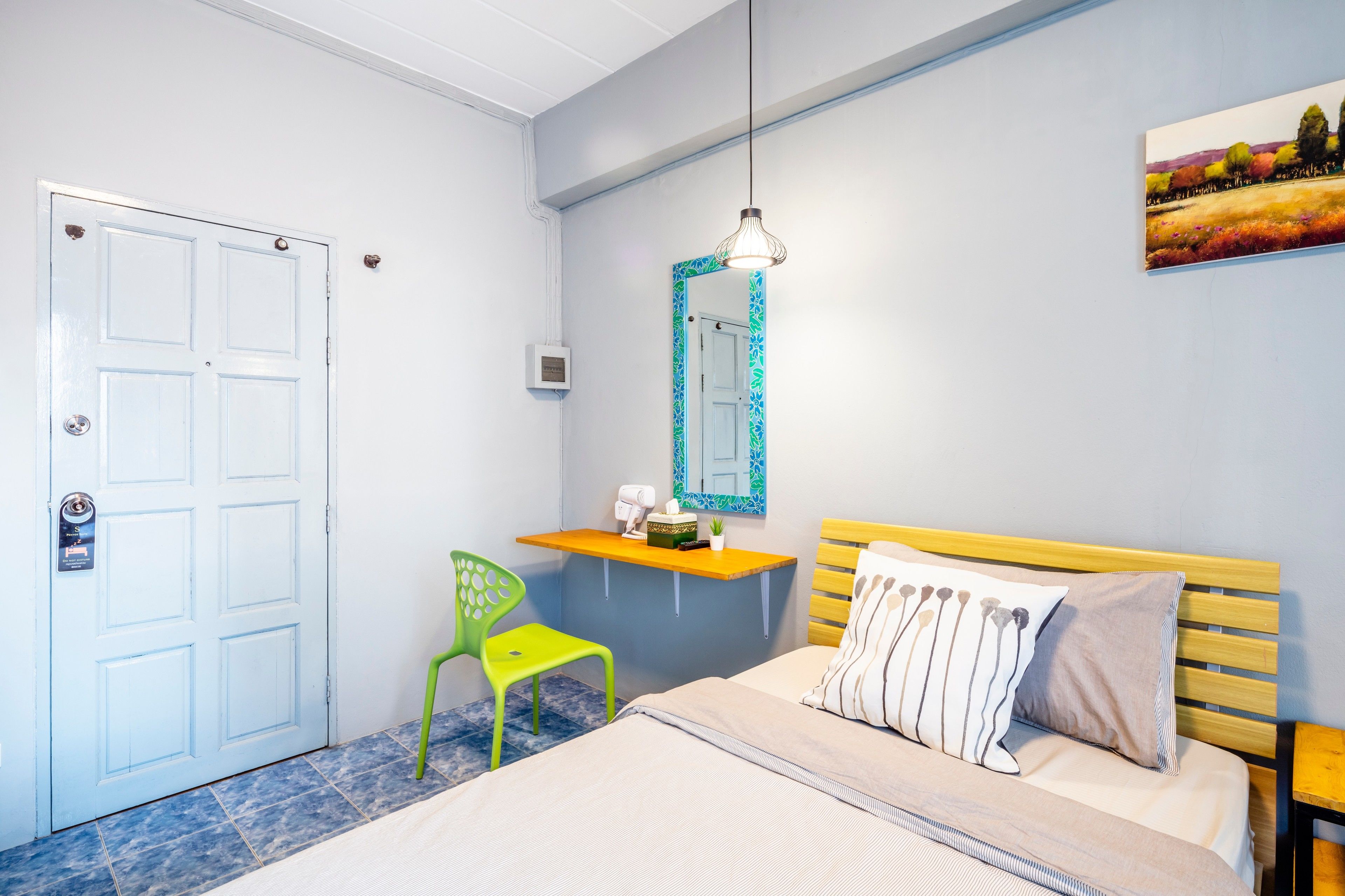 Un dormitorio con una cama, un escritorio con silla, un espejo y un cuadro en la pared.