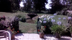 A patio with potted plants, a small pond, and a bridge in the background. - Chambres d’hôtes d'Origny-en-Thierache (Origny-en-Thierache)