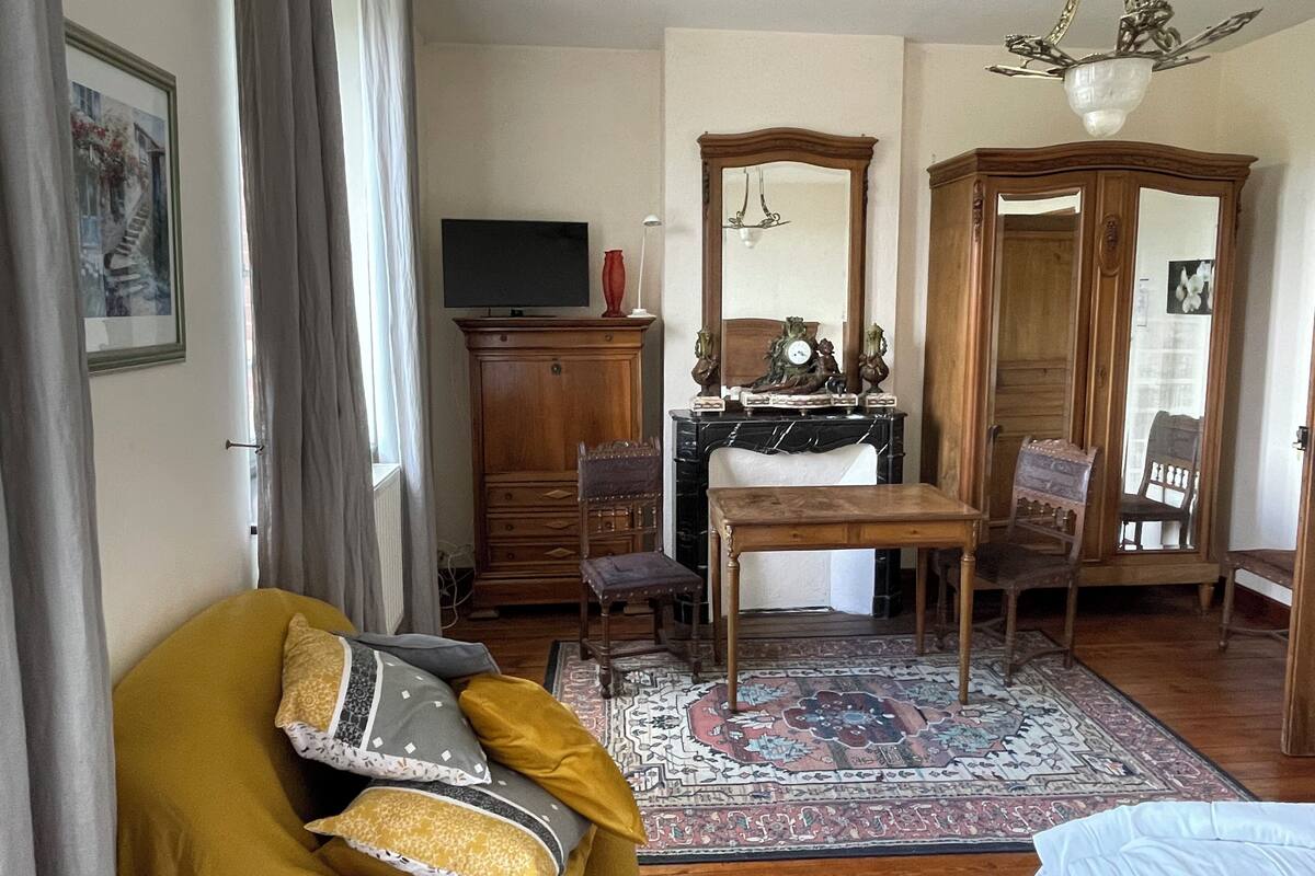 A living room with a sofa, a dining table, a TV, a fireplace, and a large mirror.