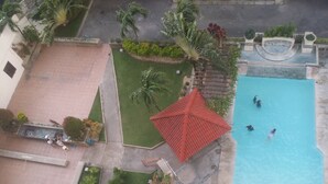 An aerial view of a courtyard with a swimming pool, palm trees, and a red-roofed structure.