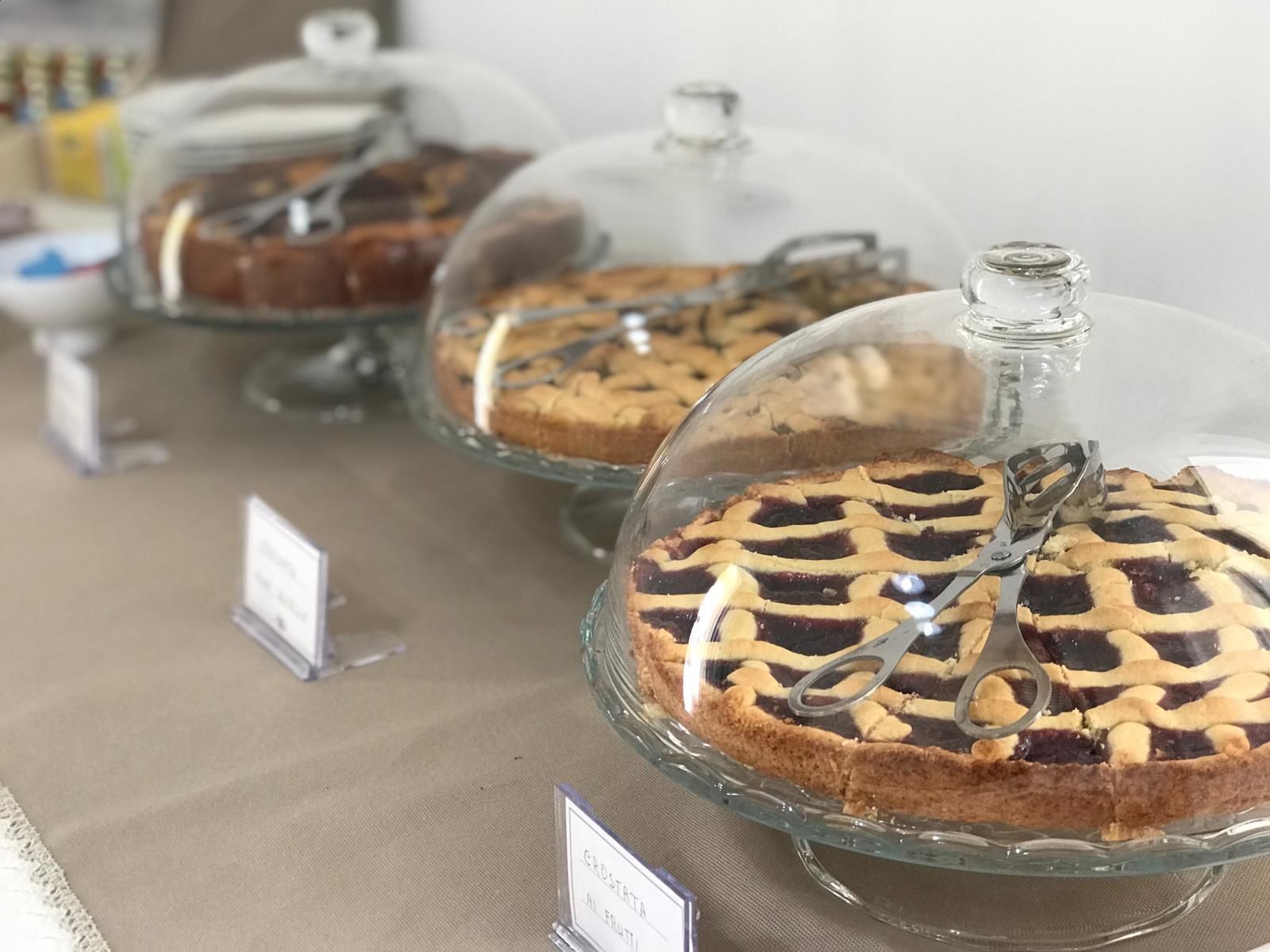 Een presentatie van taarten met duidelijke labels, waaronder een met de aanduiding 'Crostatta met Fruit'.