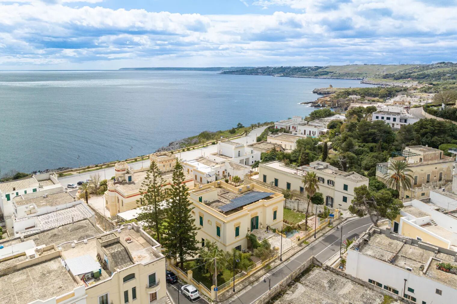 An aerial view of a coastal town with buildings, a road, and a body of water.