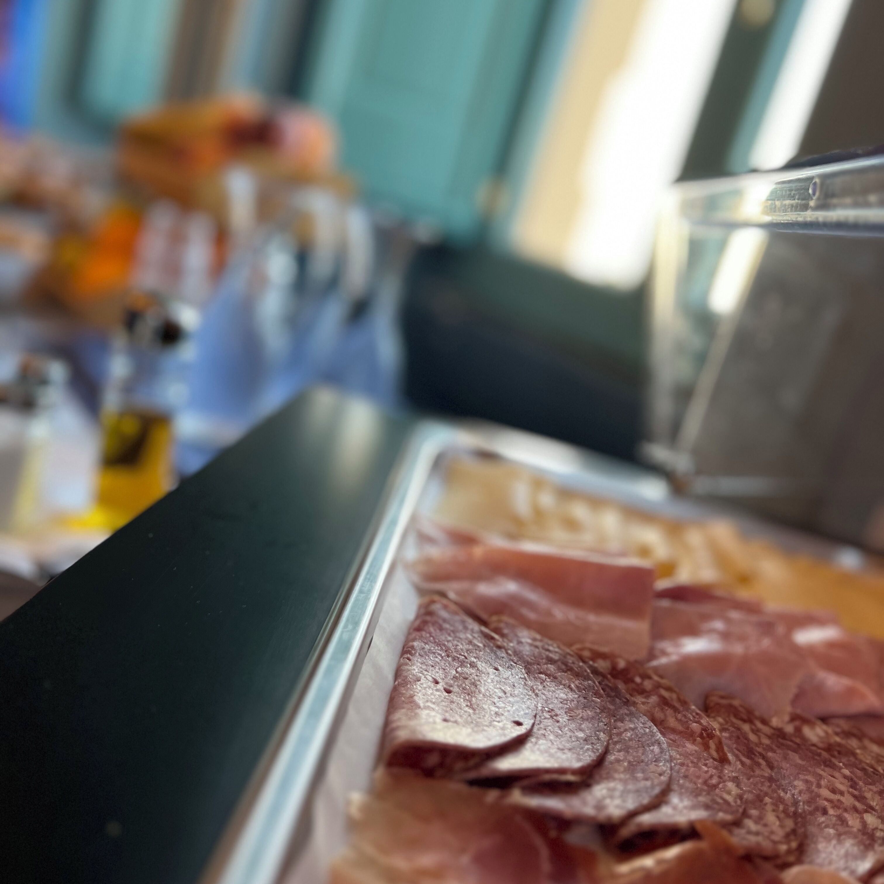 A buffet with various meats and a glass container.