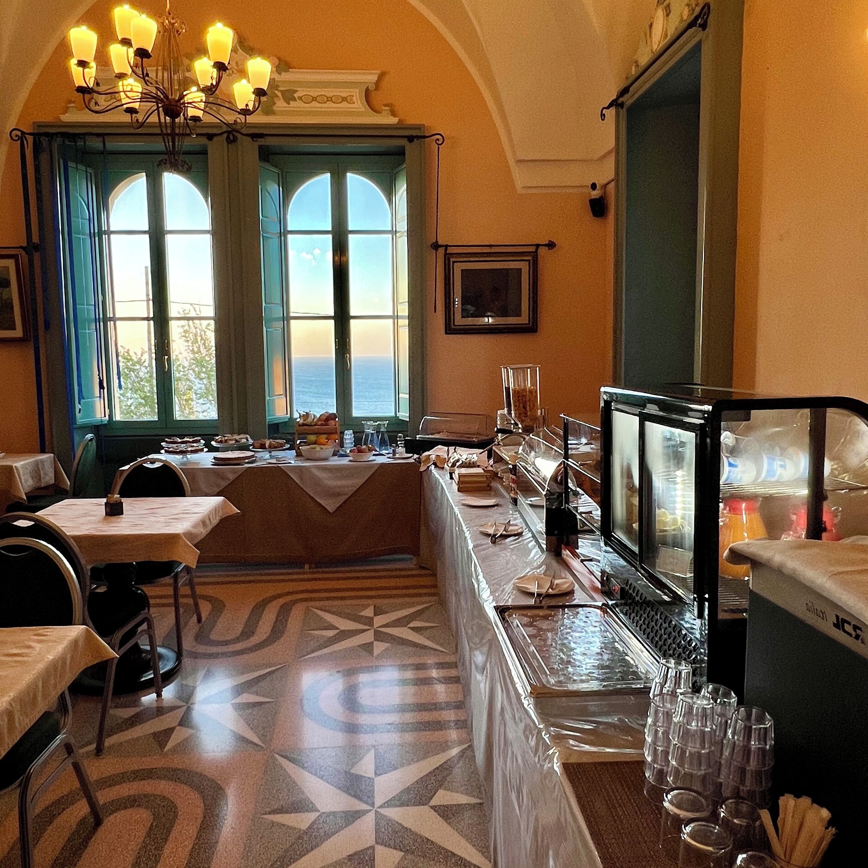 Comedor con una mesa larga, sillas, una araña y ventanas amplias con vistas.