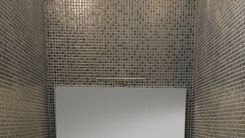 Ein Badezimmer mit einem weißen Waschbecken, einem Spiegel und einem Fön an der Wand.