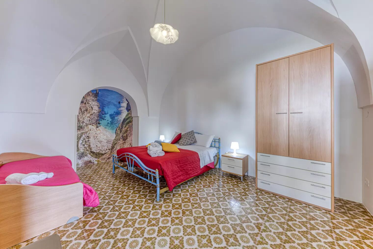Un dormitorio con cama, mesita de noche, armario y un mural en la pared.