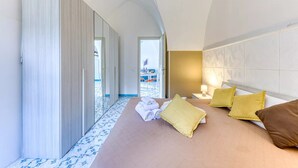 Una habitación de hotel con una cama grande, una mesita de noche y vista a la playa.