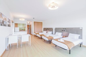 Une chambre d’hôtel avec trois lits, un coin repas et une kitchenette.