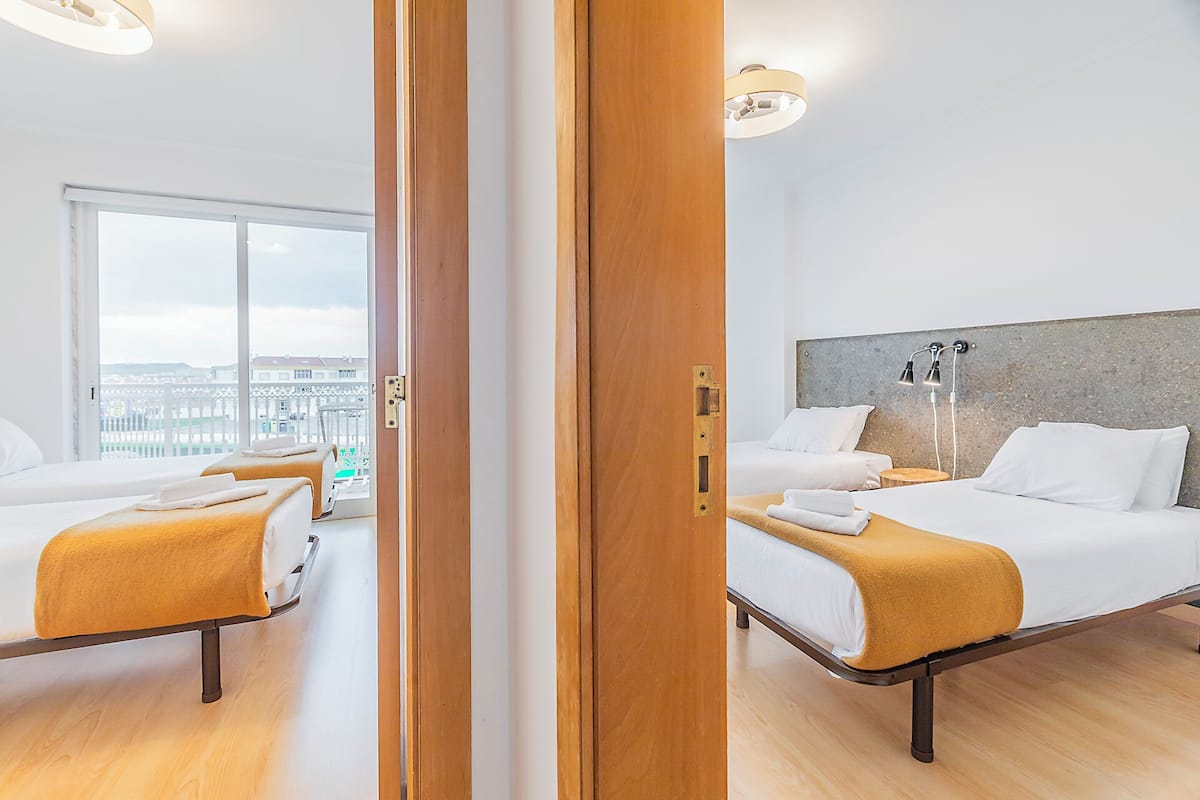 Habitación de hotel con dos camas, un ventanal grande y vistas a la ciudad.