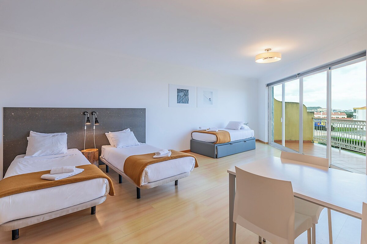 Una habitación de hotel moderna con dos camas, un escritorio y un balcón con vistas.