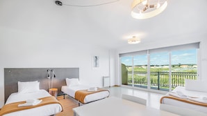 A modern hotel room with two beds, a white table, and a balcony with a view. - HI Santa Cruz - Pousada de Juventude - Hostel (Torres Vedras)